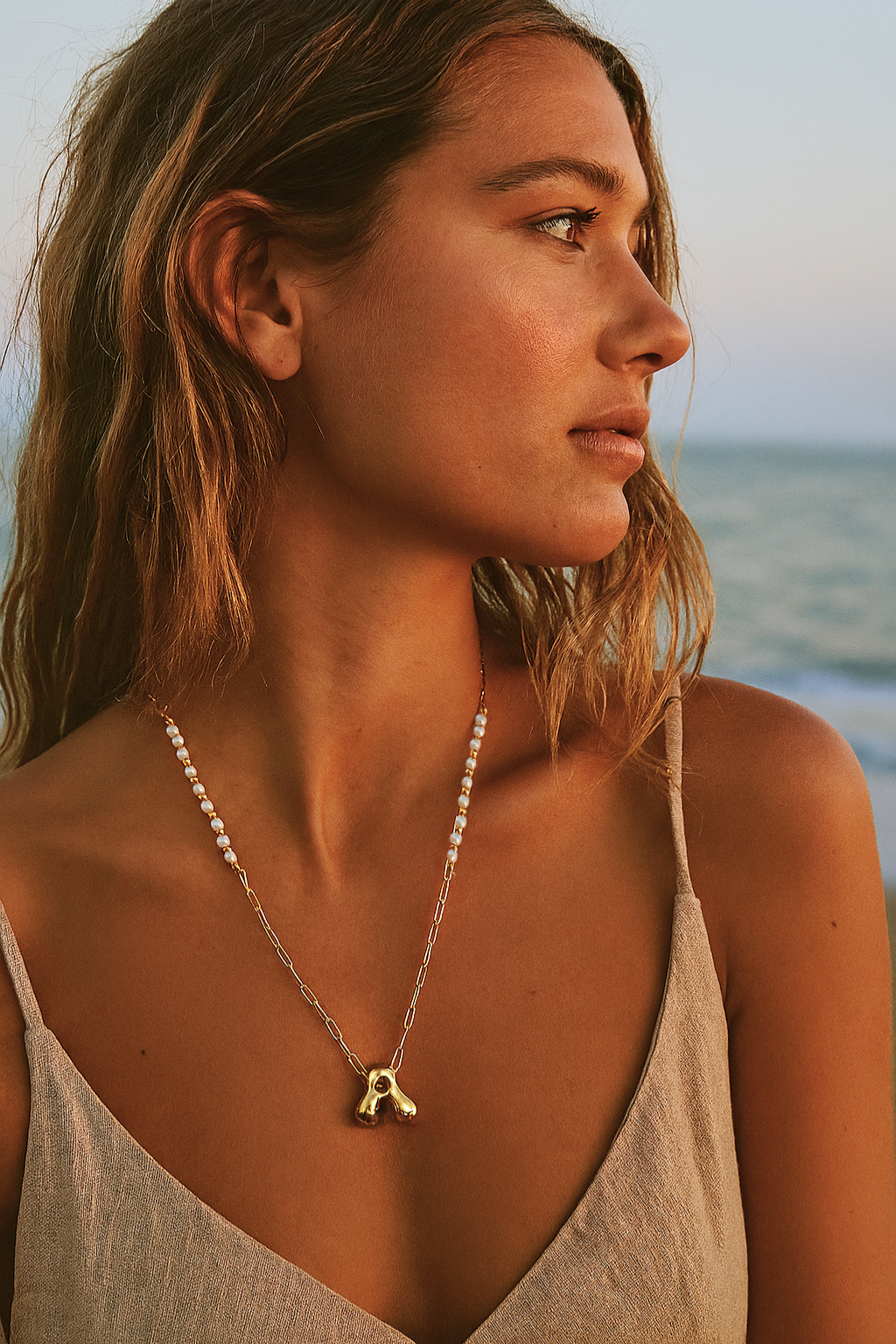 Woman wearing a necklace with a pendant against a beach background